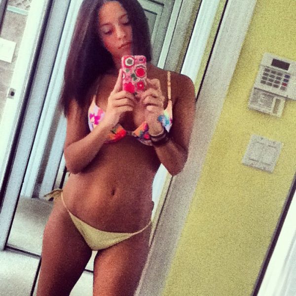 Girl with black hair taking a photo of her self in bikini.