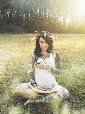 Pregnant Tattooed shick outdoors in a fieled