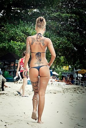 Tatooed fit girl walking on beach