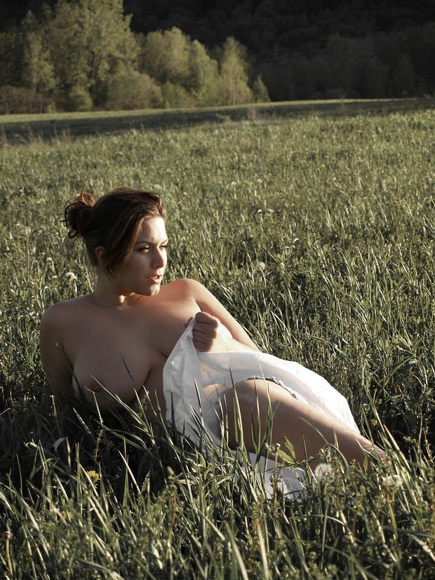 London Andrews laying nude in a field