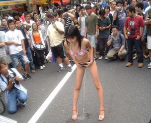 Skinny asian taking a piss in front of a crowd