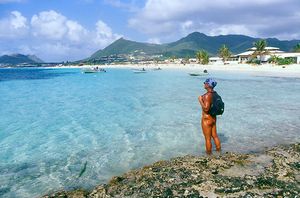 Wearing just a backpack and a head scarf, this gorgeously tanned nudist gentleman admires a beautiful tropical seascape