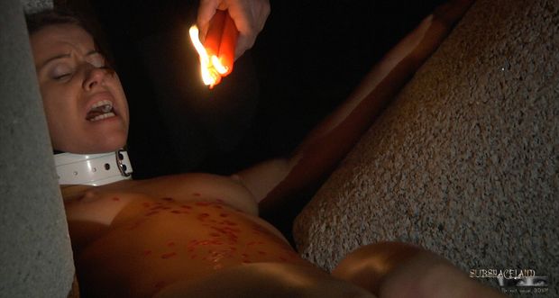 Submissive slave girl is tied up and immobilized while her master plays with her naked body. He drips hot wax on her body making her scream
