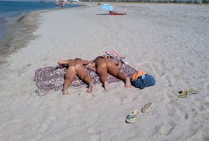 Two hot babes sunbathing nude on beach. Nice asses!