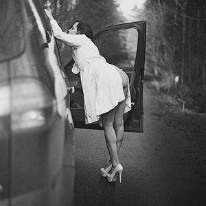 Perfect brunette in white heels and coat on the roadside.