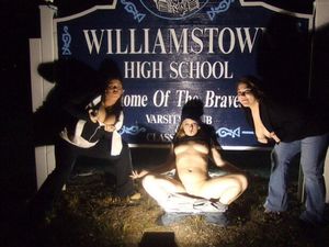 Class reunion posing in front of school sign