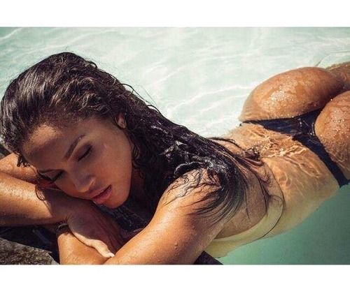 sexy ebony girl with juicy full lips and naked breasts in the pool shows her huge ass in a thong bikini