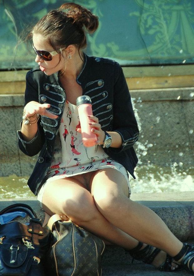 Woman sitting by fountain gives an upskirt view