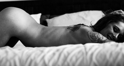 Hot brunette naked in bed with amazing tattoos on her body