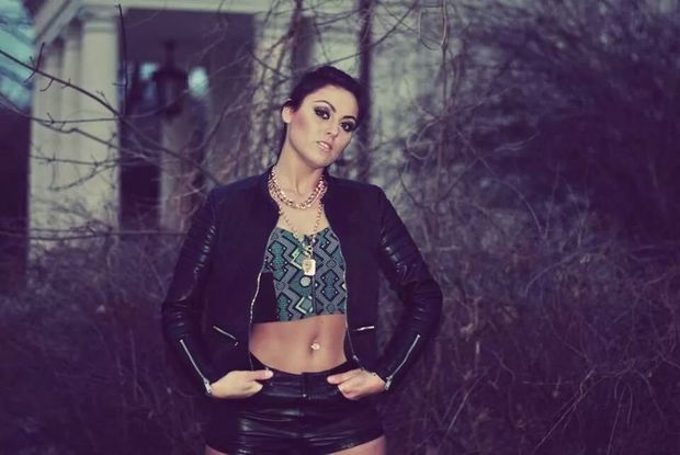 Self confident brunette chick in leather shorts and green corset in the park