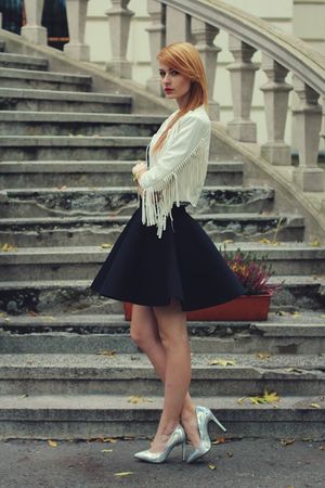 Redhead chick posing on the stairs outdoor in black skirt and stilettos