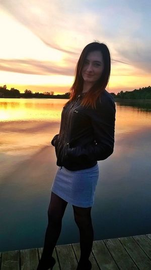 During sunset at the lake in black leather jacket, short dress and heels