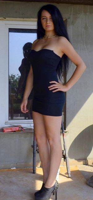 Slim tanned brunette in tight short black dress and high heels outdoor