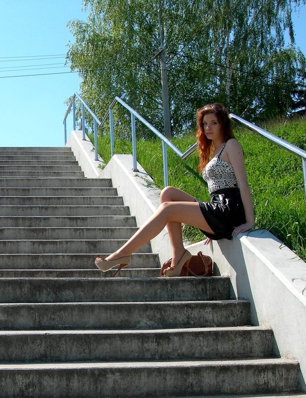 Cute sexy redhead babe sitting on a stairs