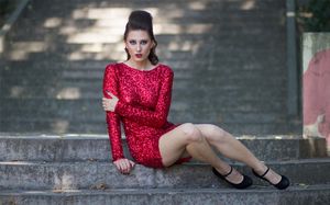 Astonishing brunette model in sparky mini dress and high heels sitting on a stairs
