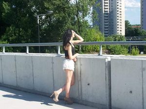 Hot young leggy brunette in sexy summer outfit and heeled ankle boots
