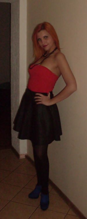 Sexy redhead chick ready for night out, braless but in red tight corset and leather skirt