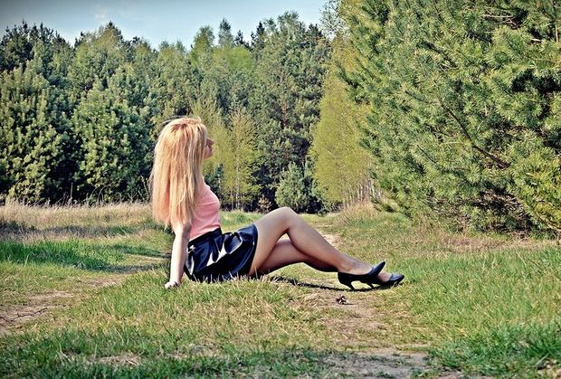 Sexy blonde chick with log legs posing outdoors in pink shirt, black latex skirt and nice stilettos