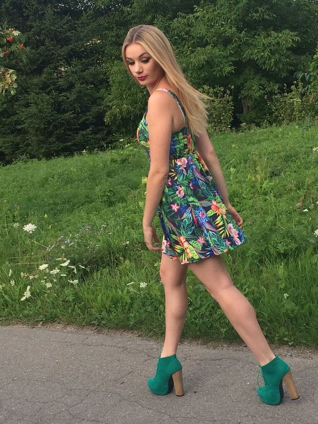Nice, leggy blonde walking through the park in summer mini dress