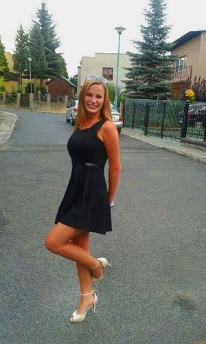 Cute redhead posing on the street in black mini dress