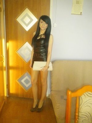 Cute short brunette in a black leather mini dress and heels before night out