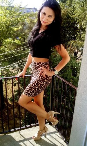 Sexy leggy brunette posing at the balcony in tight pencilskirt and high heels