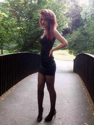 Redhead chick posing in a park wearing tight mini black leather dress