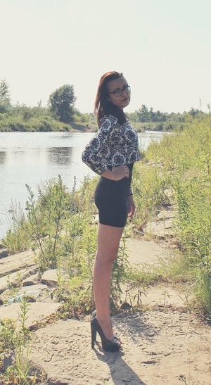 Cute brunette posing at the riverbank wearing tight short dress and high peeptoe heels