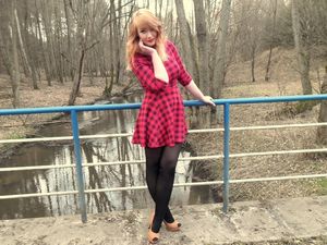 Sexy redhead girl posing outdoors in red mini dress, black pantyhose and high heels