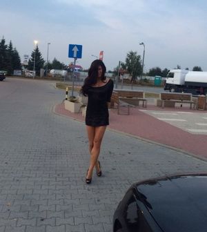 Adorable brunette in mini black dress at the parking lot