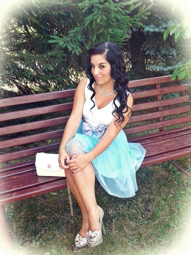 Sweet dolled up brunette sitting on the bench outdoors