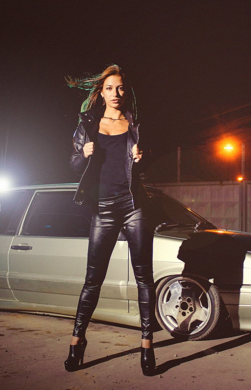 Brunette chick in leggings and boots posing with a car