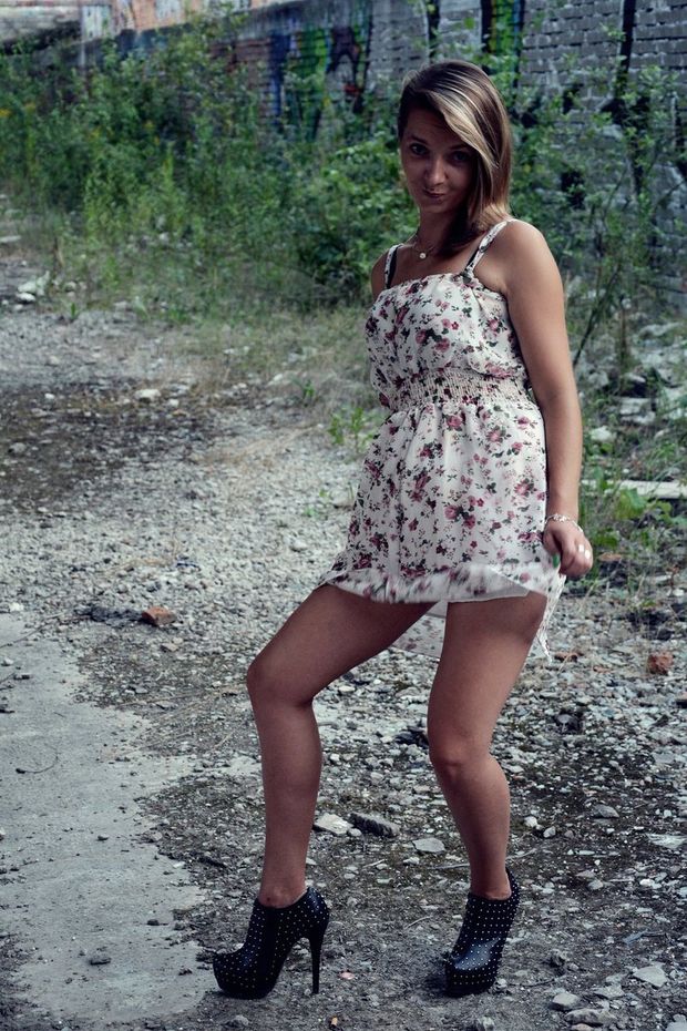 Cute blonde novice in mini dress and black leather ankle boots outdoors