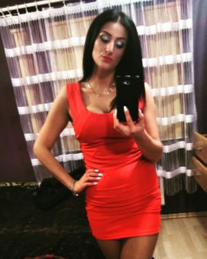 Dolled up tanned dark hair bimbo in tight mini red dress making a selfie