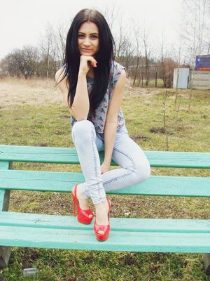 Slim brunette outdoors in high red heels