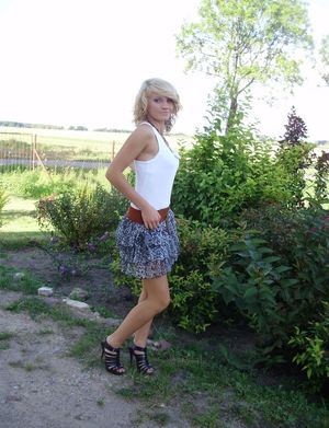 Sexy blonde countrychick posing outdoors in mini skirt and tight top