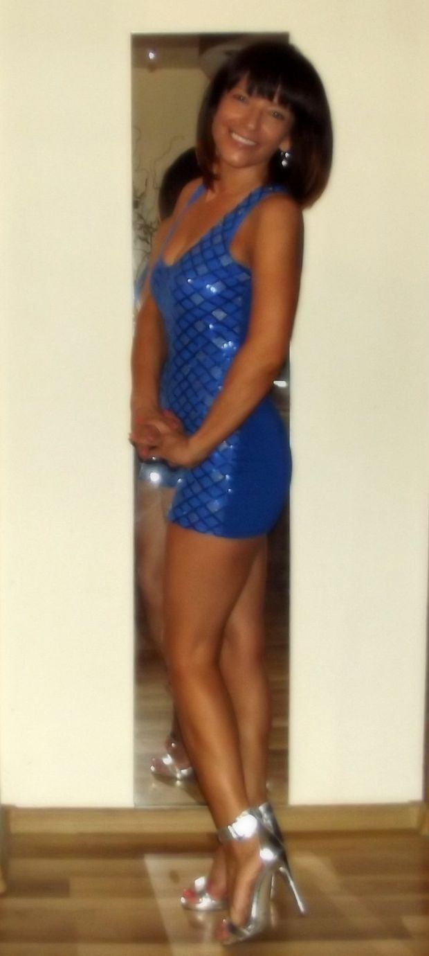 Damm sexy milf posing at home in cute shiny blue mini dress and high heeled silver sandals