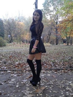Sexy rookie posing in the park, wearing nasty black outfit, high heels, knee highs, latex mini skirt and lace blouse
