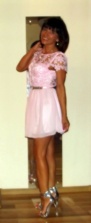 Tanned mature posing at home in cute pink mini dress