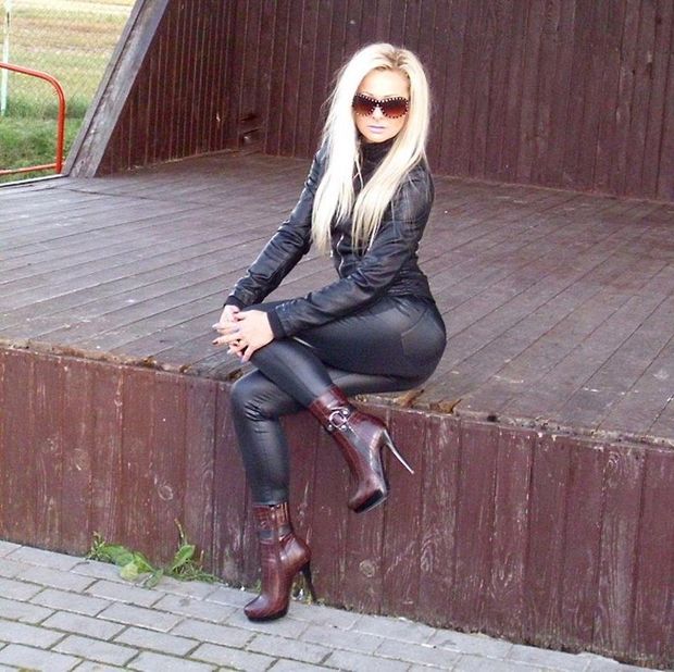 Blonde bimbo posing outdoors in tight latex outfit and high heeled leather ankle boots