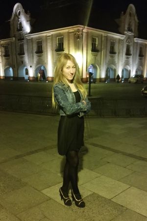 Nice chick posing outdoors on the street in thin loose black mini dress and ankle boots