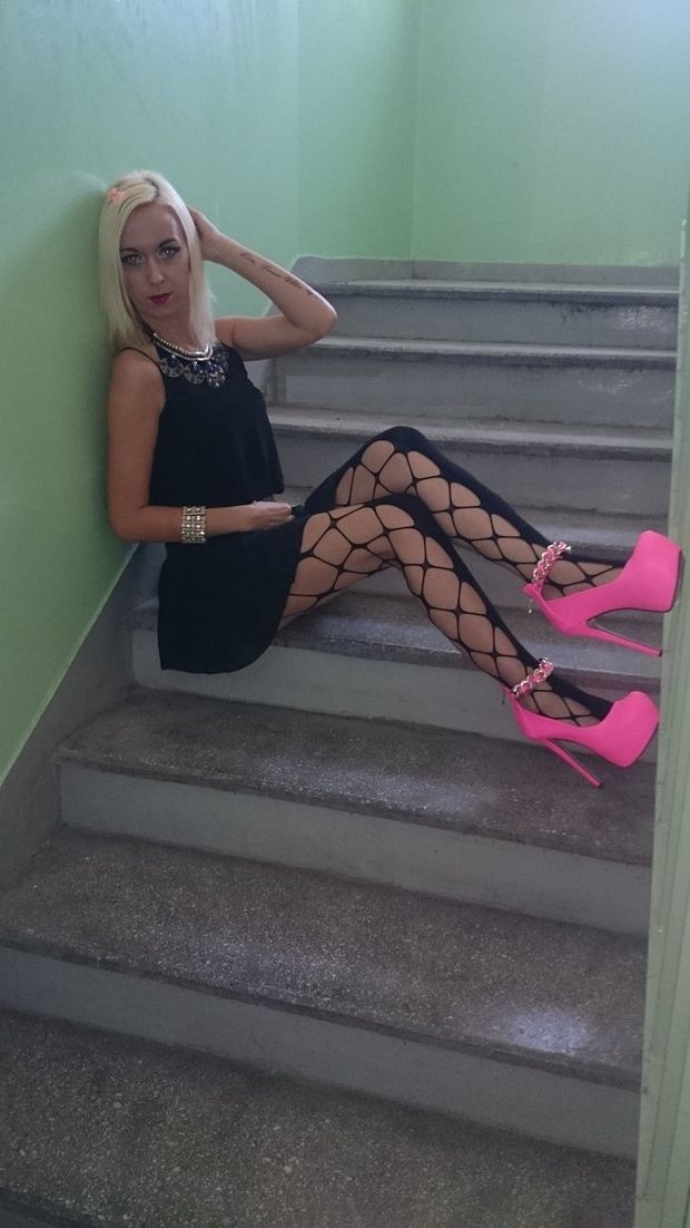 Blonde bimbo posing in pink high platform heels at the staircase