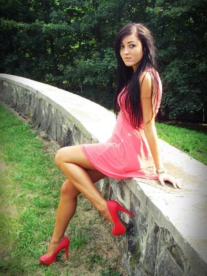 Sexy brunette babe in pink summer dress and red high heels outdoors