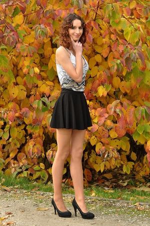 Sexy leggy brunette posing in a park wearing short black mini skirt and nice clevy shirt