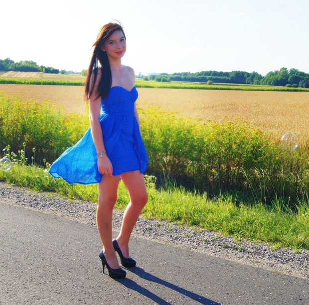 Nice brunette posing on a countryside road in loose blue mini dress
