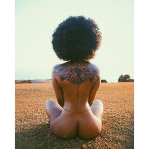 Tattooed ebony female in a barren field