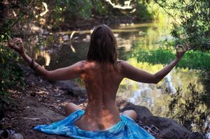 Brunette nymph meditating by a lake