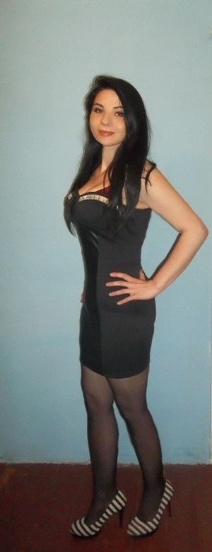 Busty brunette in really tight, smooth black mini dress