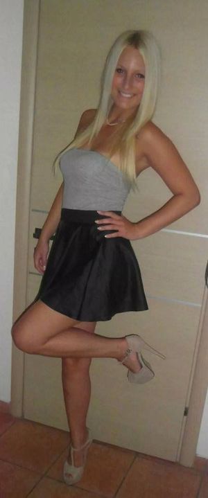 Tanned busty blonde in seductive outfit and high heels