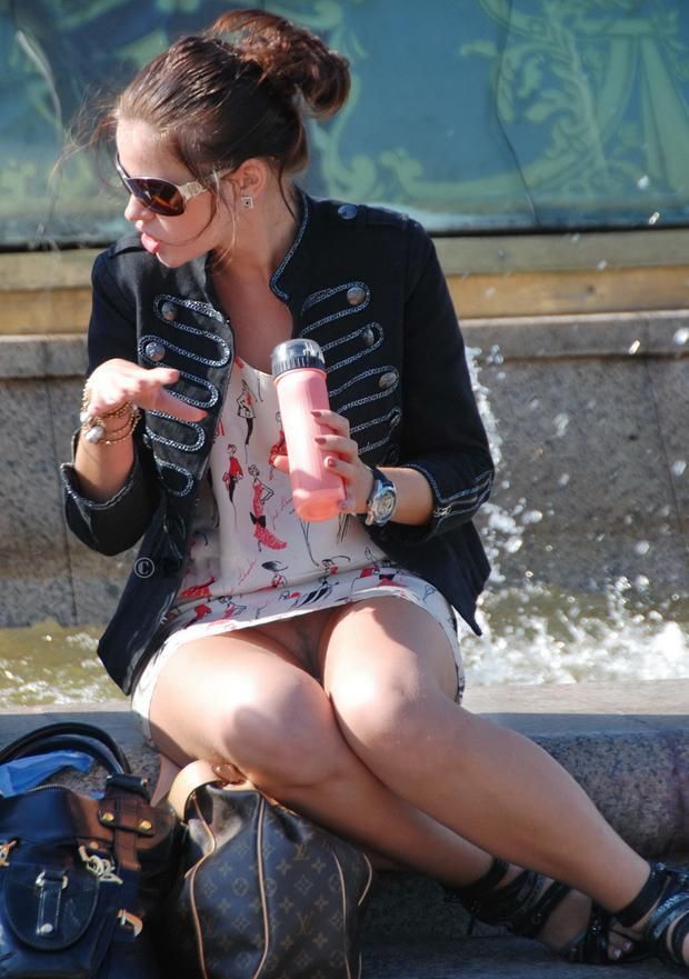 Woman sitting by fountain gives an upskirt view
